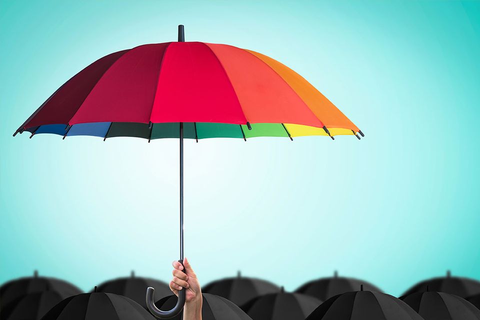 Image of a hand holding a colourful umbrella above a group of black umbrellas to symbolize cyber coverage.